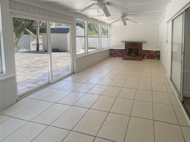 unfurnished sunroom with a fireplace and ceiling fan