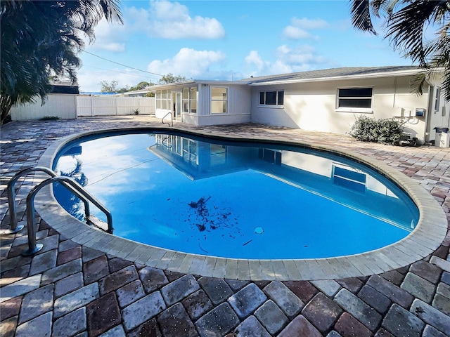 view of pool with an outdoor structure, fence, a sunroom, a fenced in pool, and a patio area