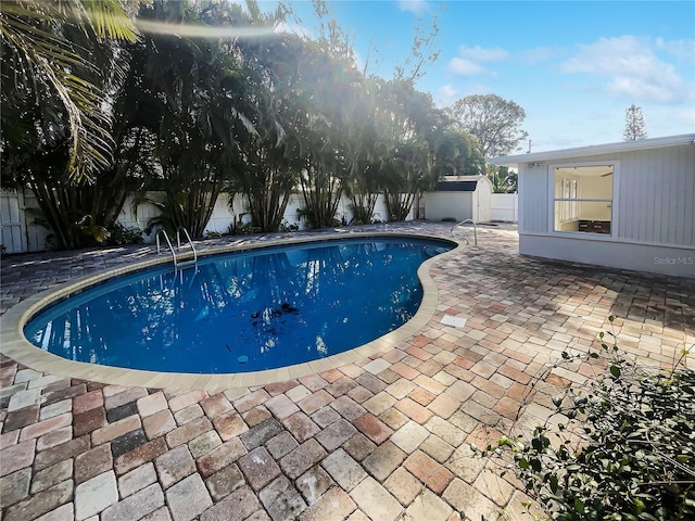 view of pool with a fenced backyard, an outdoor structure, a fenced in pool, and a patio