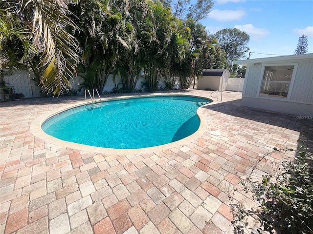 view of swimming pool featuring an outbuilding, a patio area, a fenced backyard, and a fenced in pool