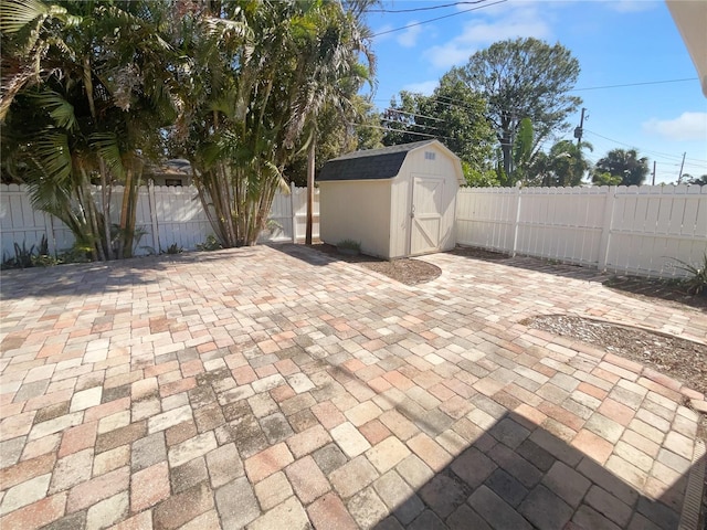 view of patio with a storage shed, a fenced backyard, and an outbuilding