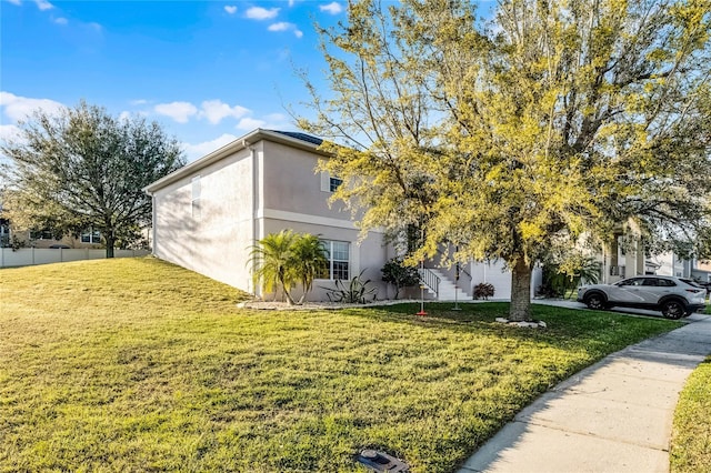 view of property exterior with a lawn, fence, and stucco siding