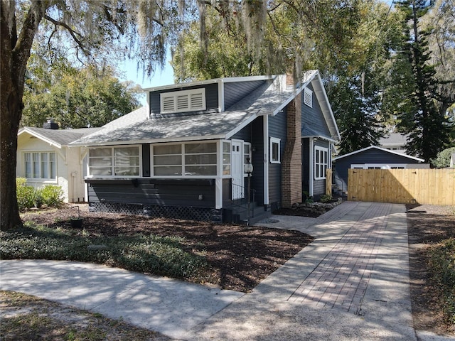 bungalow-style home with entry steps, a chimney, and fence