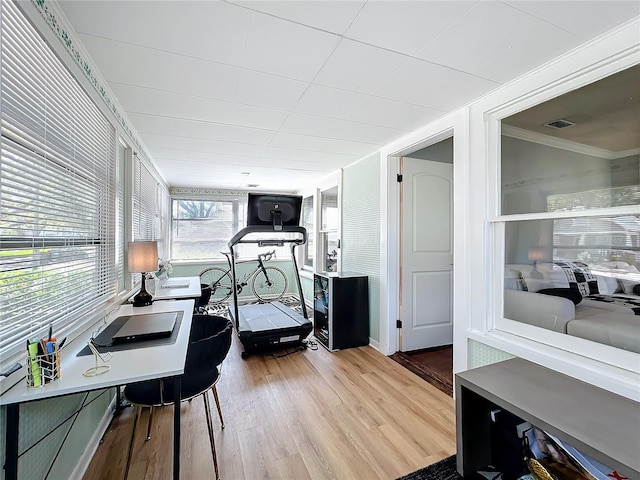 interior space with wood finished floors, visible vents, and crown molding