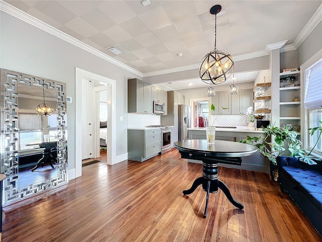 interior space with visible vents, an inviting chandelier, ornamental molding, wood finished floors, and baseboards