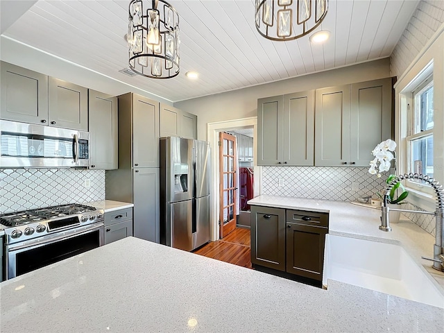 kitchen featuring stainless steel appliances, a chandelier, a sink, and gray cabinets