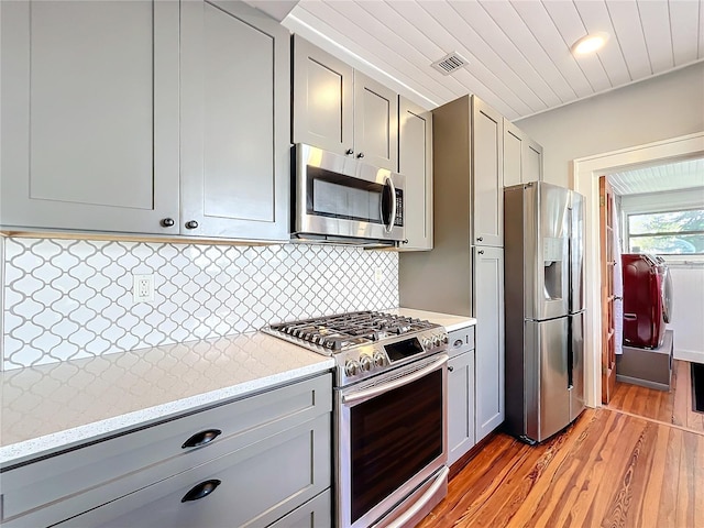 kitchen with visible vents, light wood-style floors, appliances with stainless steel finishes, gray cabinets, and tasteful backsplash