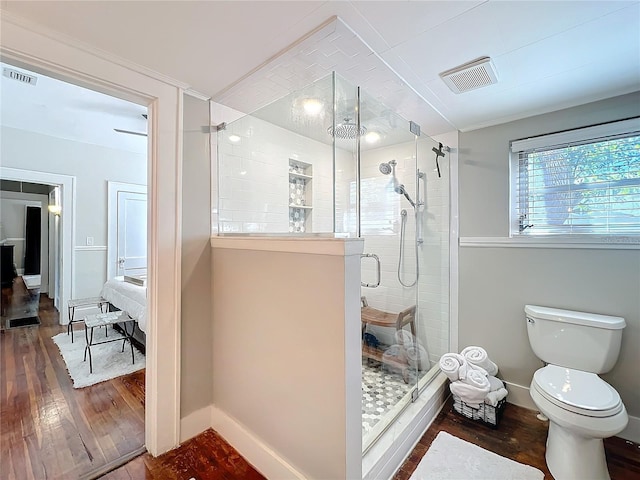 bathroom with visible vents, toilet, a stall shower, wood finished floors, and baseboards