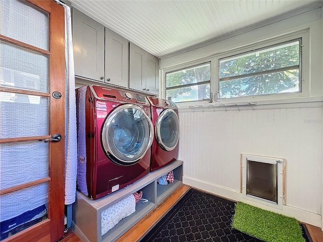 washroom with a healthy amount of sunlight, cabinet space, washing machine and clothes dryer, and wood finished floors