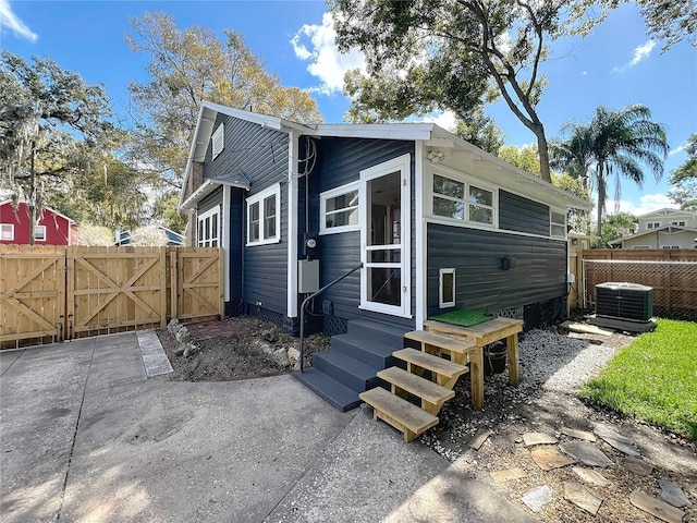 rear view of property featuring entry steps, fence, and a gate