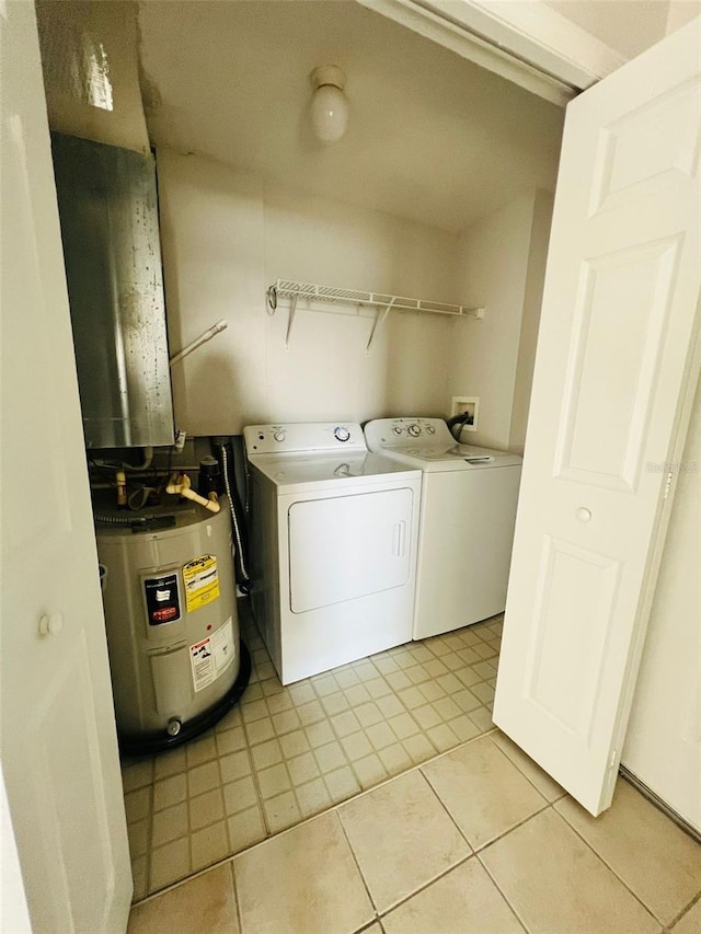 washroom with water heater, laundry area, light tile patterned floors, and washer and dryer