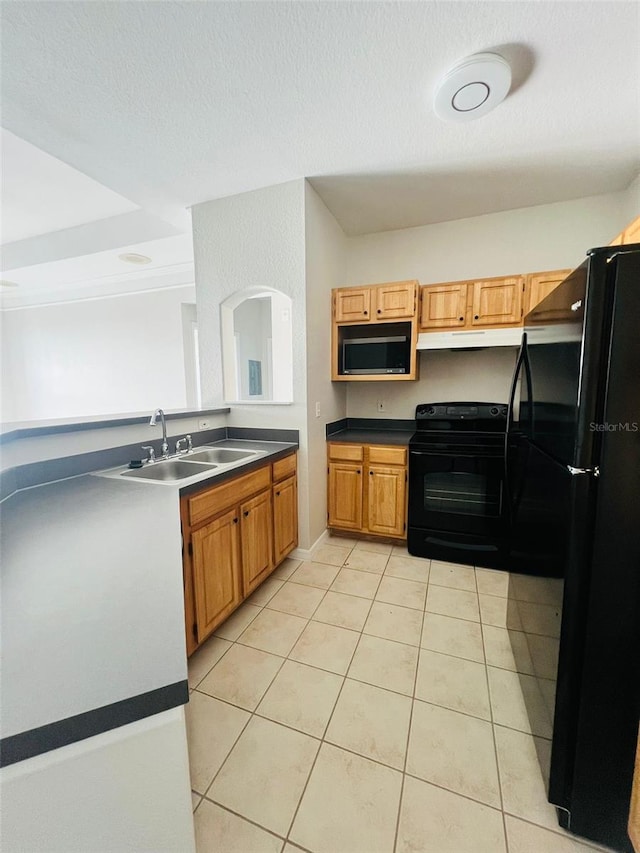 kitchen featuring light tile patterned floors, under cabinet range hood, a sink, black appliances, and dark countertops