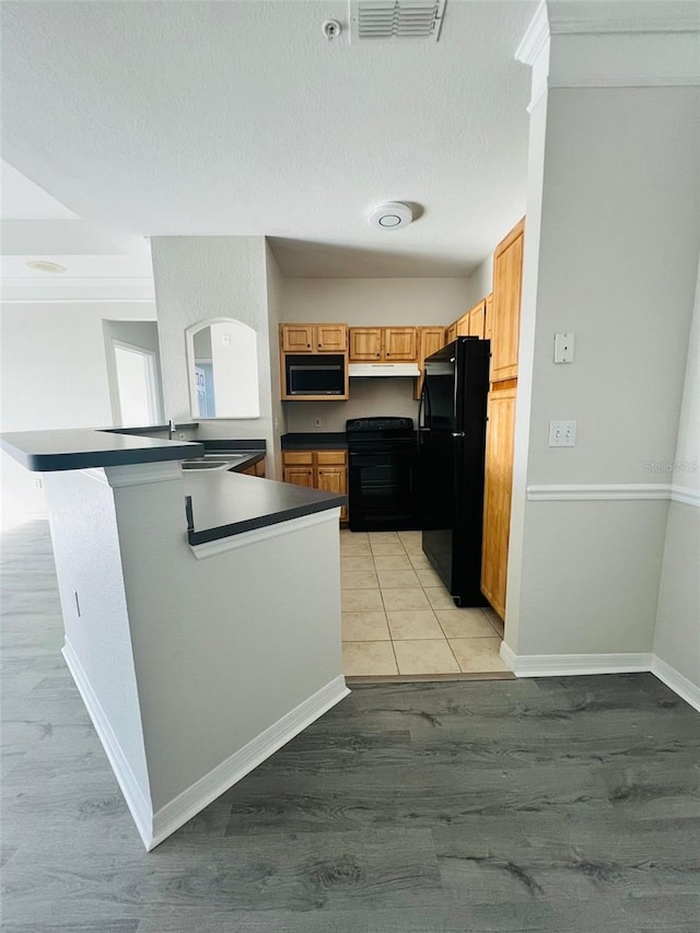 kitchen featuring dark countertops, black appliances, visible vents, and light wood-style floors