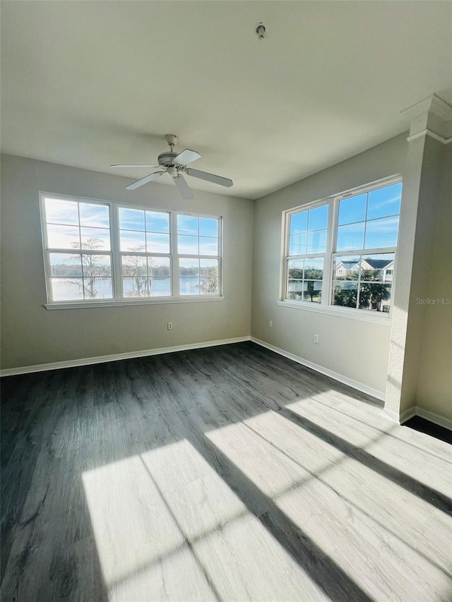 unfurnished room featuring a ceiling fan, baseboards, and dark wood-style flooring