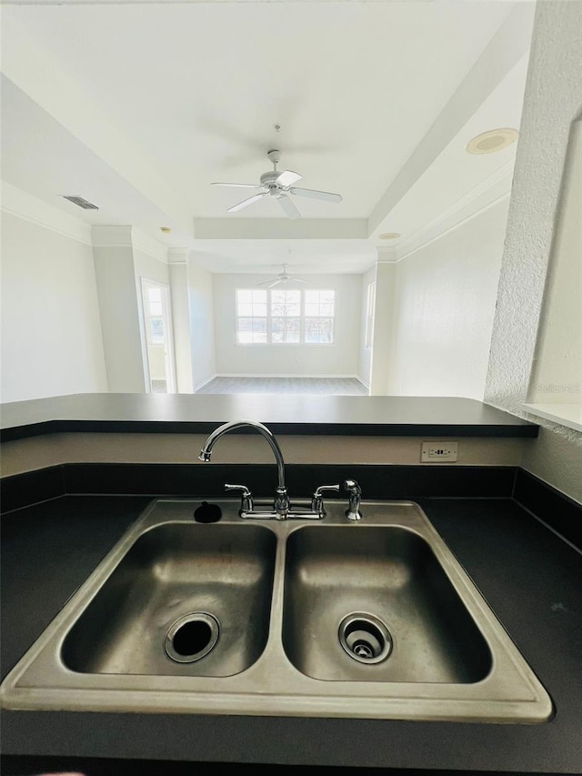 room details featuring visible vents, a ceiling fan, dark countertops, ornamental molding, and a sink