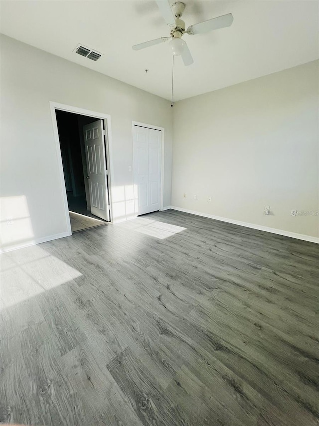 spare room featuring a ceiling fan, visible vents, baseboards, and wood finished floors