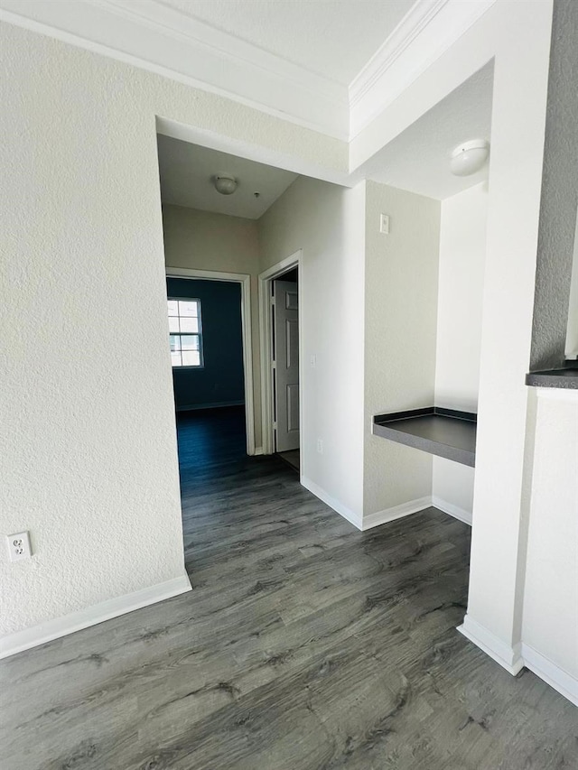 corridor with baseboards, ornamental molding, wood finished floors, and a textured wall