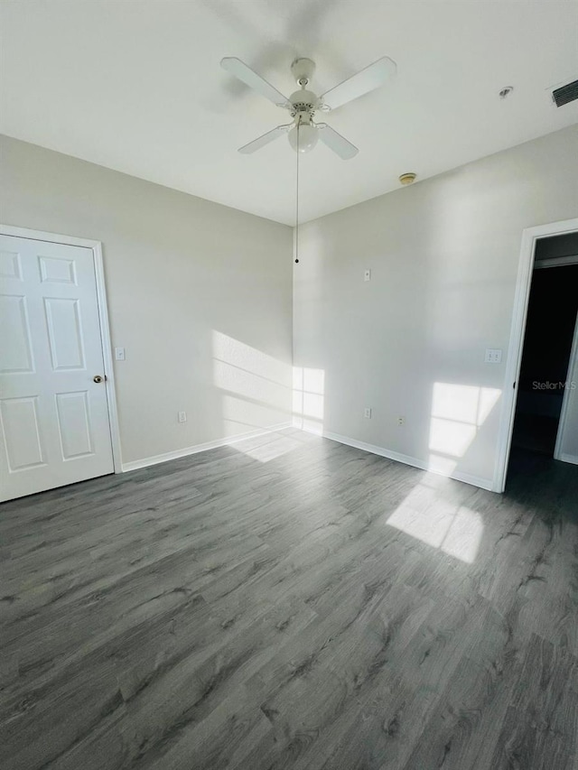 spare room featuring dark wood-type flooring, visible vents, ceiling fan, and baseboards