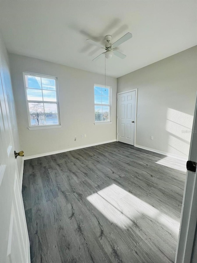 unfurnished bedroom with ceiling fan, baseboards, and dark wood finished floors