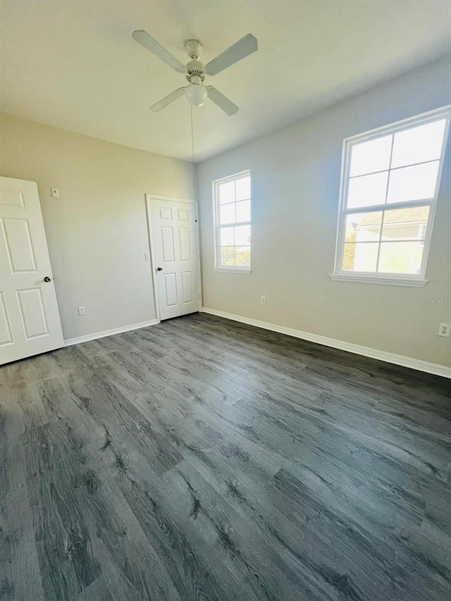 unfurnished bedroom with dark wood-style flooring, a ceiling fan, and baseboards