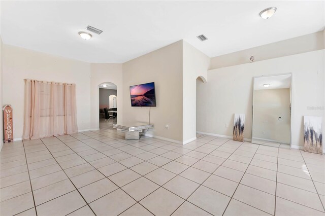 68 Herring Ct, Kissimmee, FL 34759 - unfurnished living room with light tile patterned floors, visible vents, arched walkways, and baseboards