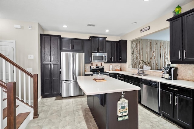 kitchen with dark cabinets, stainless steel appliances, a sink, visible vents, and a center island