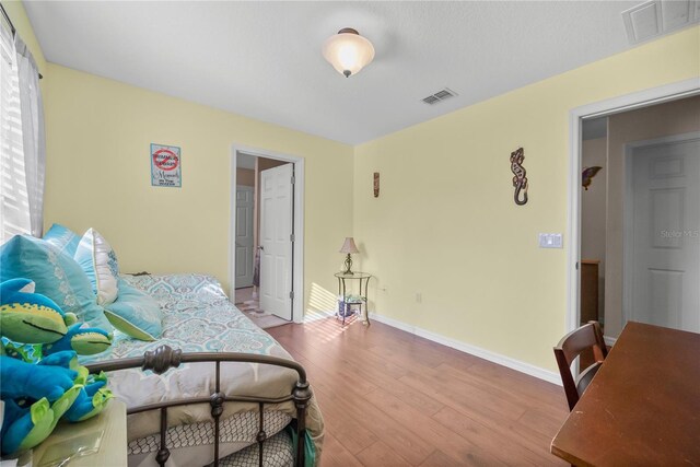 bedroom featuring wood finished floors, visible vents, and baseboards