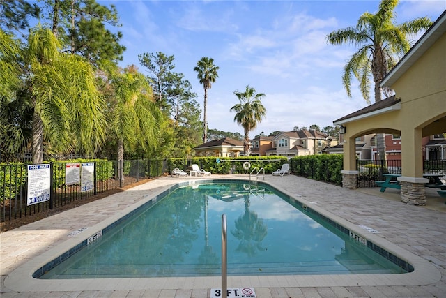 pool with a patio area and fence