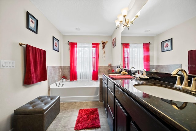 full bathroom with a bath, double vanity, a chandelier, and a sink