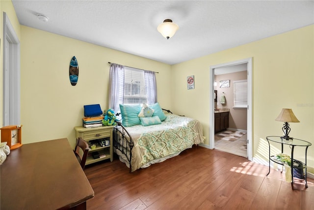 bedroom featuring ensuite bath, hardwood / wood-style flooring, and baseboards