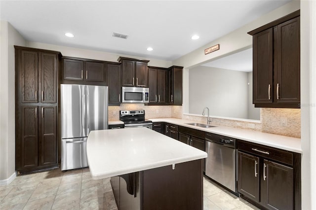 2015 Shalimar Loop, Sanford, FL 32773 - kitchen with appliances with stainless steel finishes, a sink, dark brown cabinets, a kitchen island, and decorative backsplash