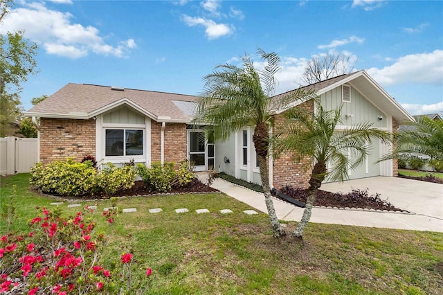 ranch-style home featuring brick siding, board and batten siding, an attached garage, and a front yard