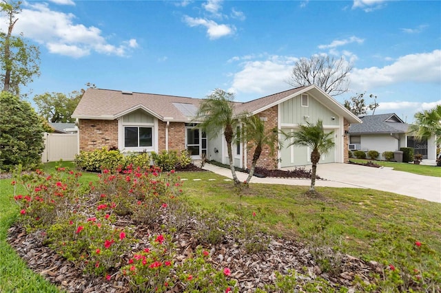 ranch-style home featuring brick siding, concrete driveway, an attached garage, board and batten siding, and a front yard