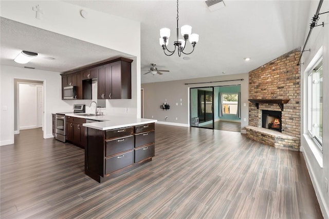 kitchen with visible vents, open floor plan, dark brown cabinets, appliances with stainless steel finishes, and a brick fireplace