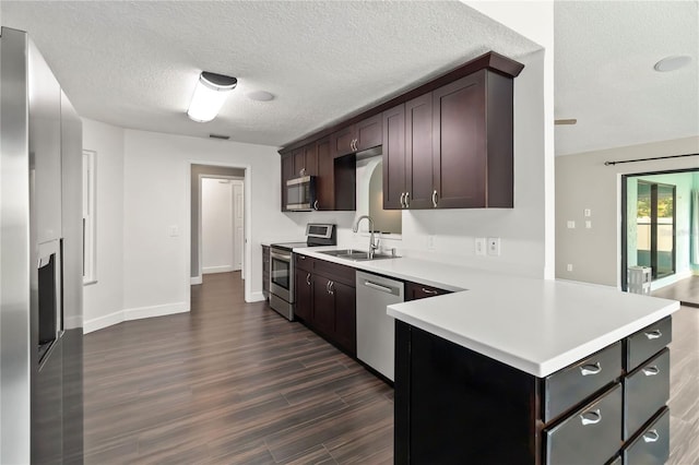 kitchen with dark brown cabinetry, a sink, light countertops, appliances with stainless steel finishes, and dark wood finished floors