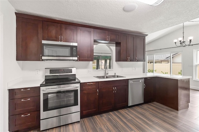 kitchen featuring stainless steel appliances, a peninsula, a sink, and light countertops