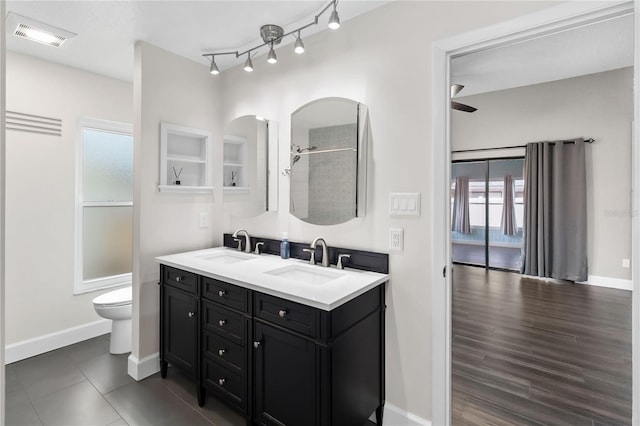 full bathroom with double vanity, baseboards, visible vents, and a sink