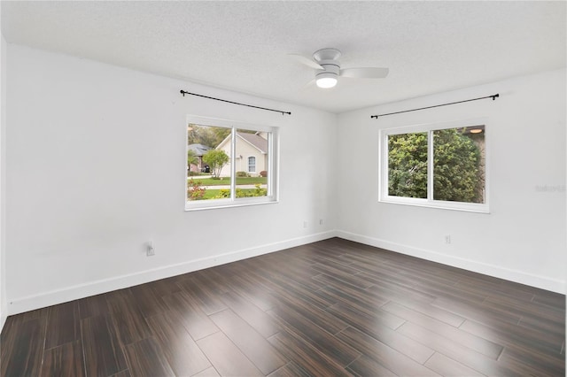 spare room with dark wood-style floors, a ceiling fan, baseboards, and a textured ceiling