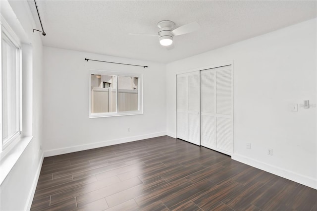 unfurnished bedroom with a closet, dark wood finished floors, a textured ceiling, and baseboards