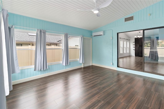 empty room featuring a wall unit AC, ceiling fan with notable chandelier, wood finished floors, visible vents, and vaulted ceiling