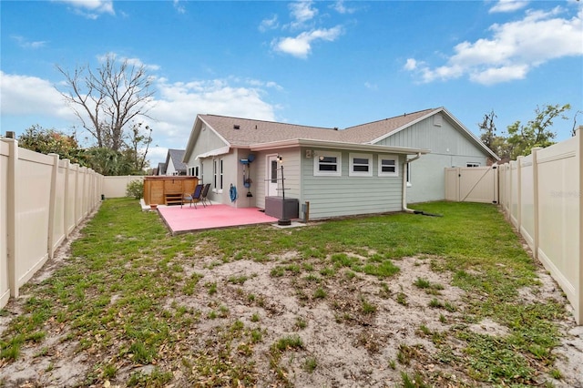 rear view of house featuring a yard, a fenced backyard, and a patio