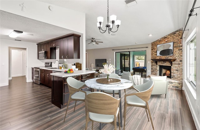 dining space featuring a fireplace, visible vents, vaulted ceiling, and dark wood-type flooring