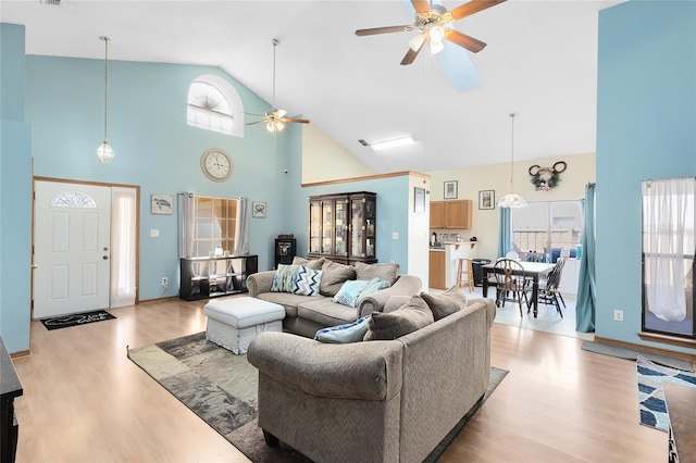 living area featuring ceiling fan, high vaulted ceiling, and wood finished floors