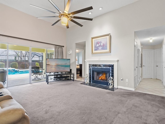 carpeted living area featuring recessed lighting, a high ceiling, ceiling fan, a tile fireplace, and baseboards