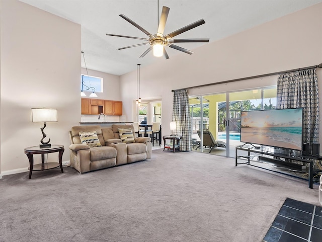 living room featuring carpet floors, a high ceiling, baseboards, and a ceiling fan