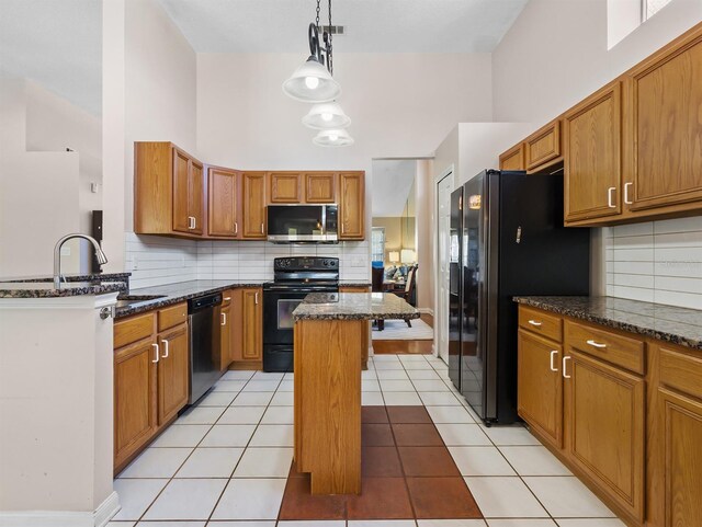 kitchen featuring black appliances, dark stone countertops, a sink, and brown cabinets