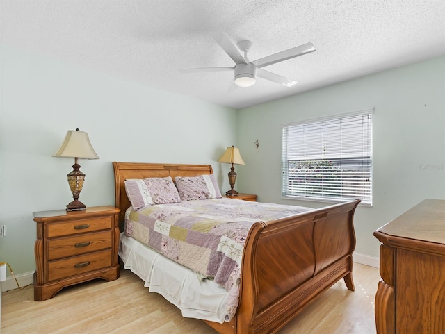 bedroom with a textured ceiling, ceiling fan, light wood-type flooring, and baseboards