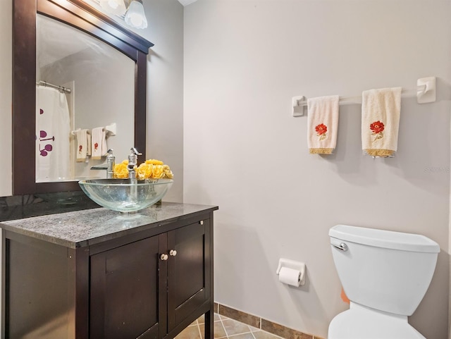 bathroom with toilet, tile patterned floors, baseboards, and vanity