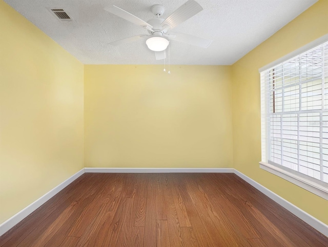 spare room with baseboards, visible vents, dark wood finished floors, and a textured ceiling