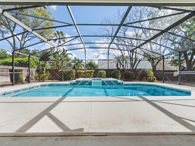 view of pool with a lanai, a pool with connected hot tub, fence, and a patio